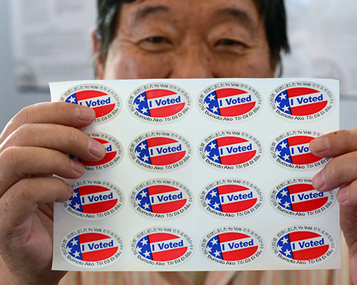 man holding sheet of "i voted" stickers